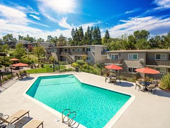 A swimming pool surrounded by lounge chairs and umbrellas in a residential area at Pleasanton Heights, Pleasanton, CA